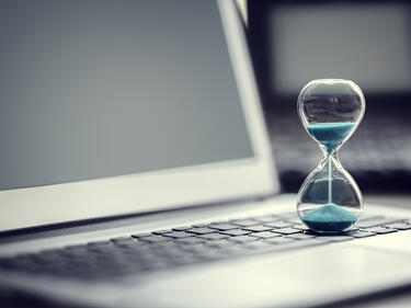 Hourglass on laptop computer concept for time management and countdown to deadline