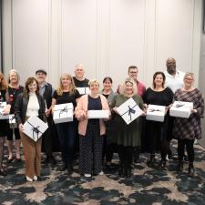 Group of employees holding white boxes, celebrating years of service