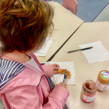 Student putting peanut butter and jam on a piece of toast